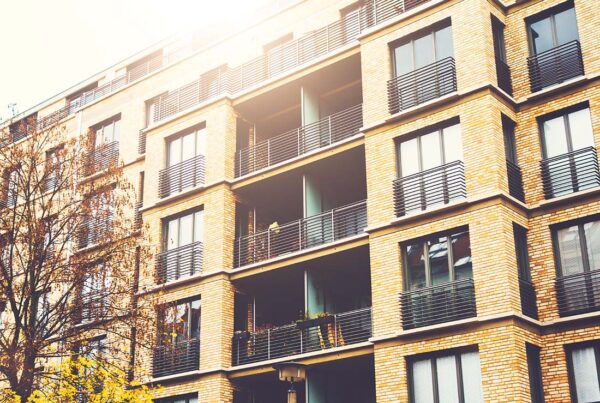 Landlord and Rental Property Insurance - Angled View of a Modern Brick Apartment Building With Warm Sunlight Shining From Above