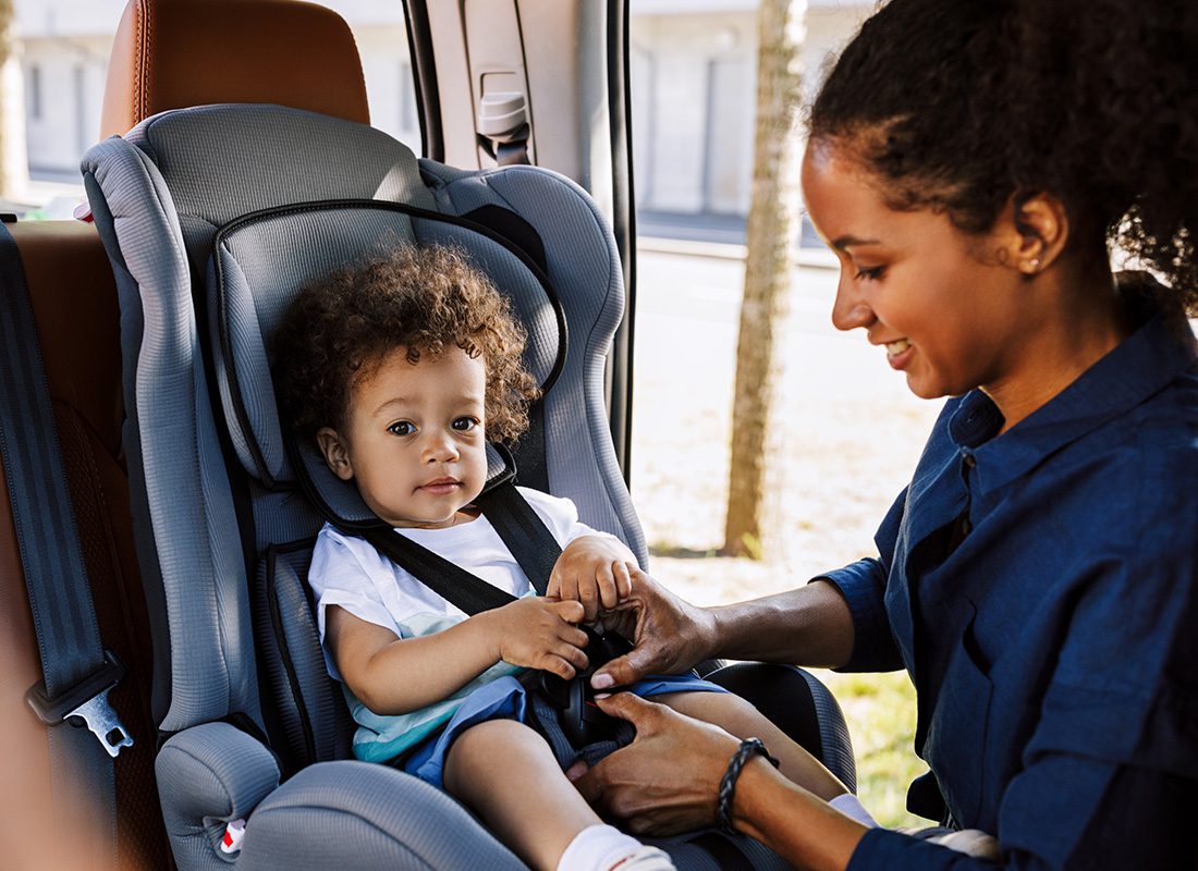 Personal Insurance - Happy Mother Buckles Her Baby into a Carseat in a Car